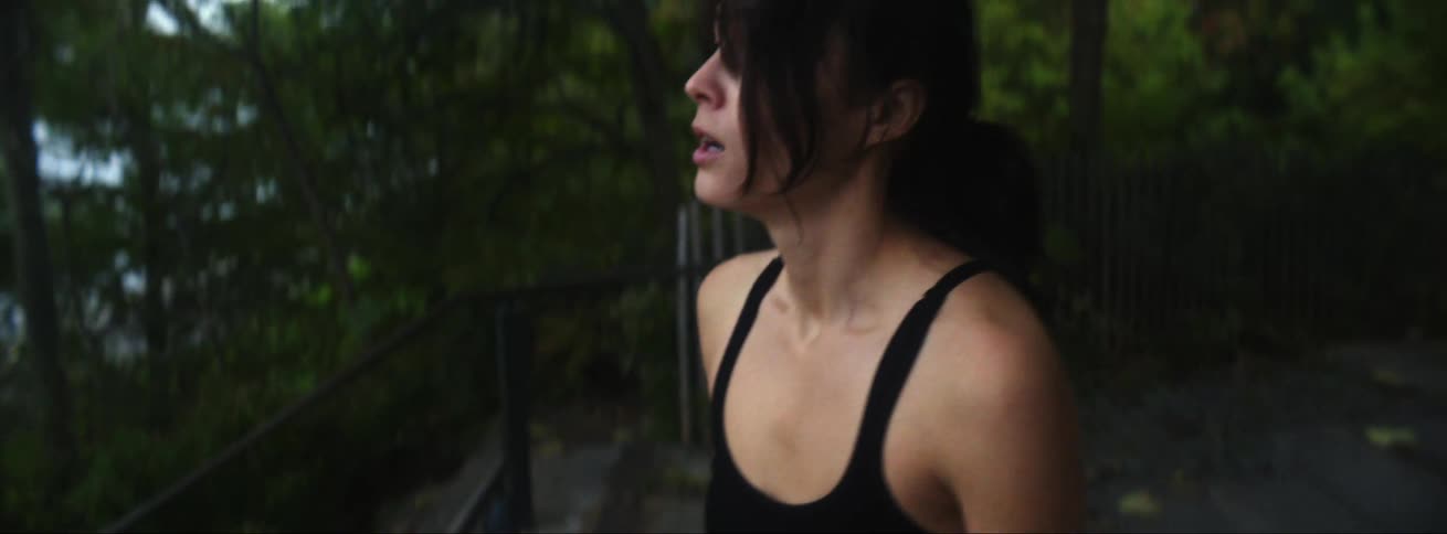 Young woman wearing sports clothes jogging in a park takes a pause before running again