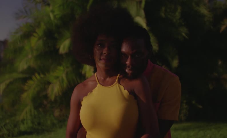 Man glares while back hugging woman outdoors