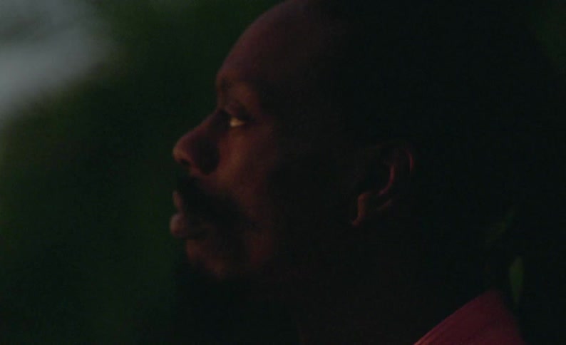 Side profile of male dancer with mustache and braids at dusk