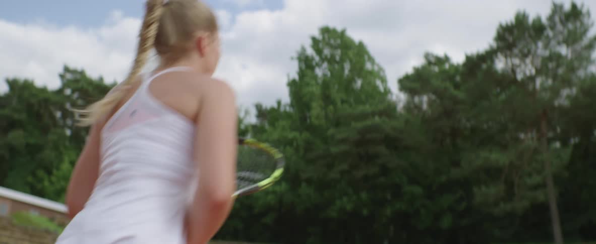White girl wearing a white tennis clothing playing tennis in a tennis court