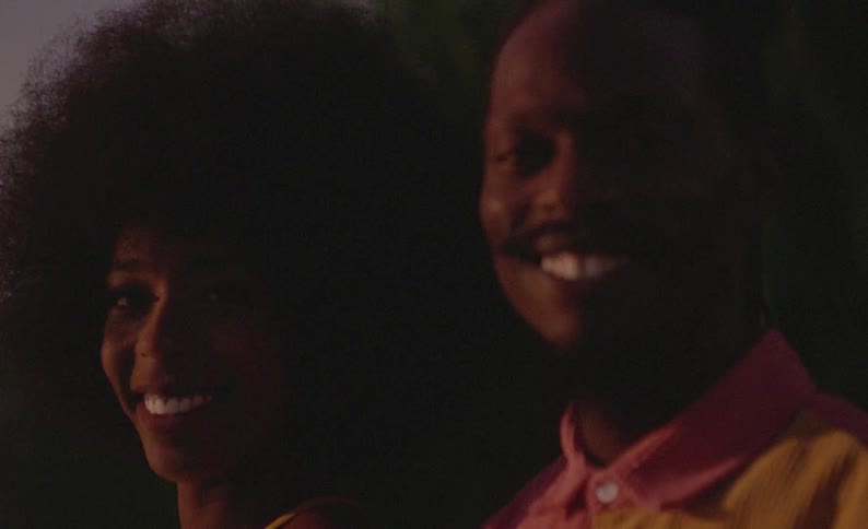 A man and woman pose together outside at night while smiling