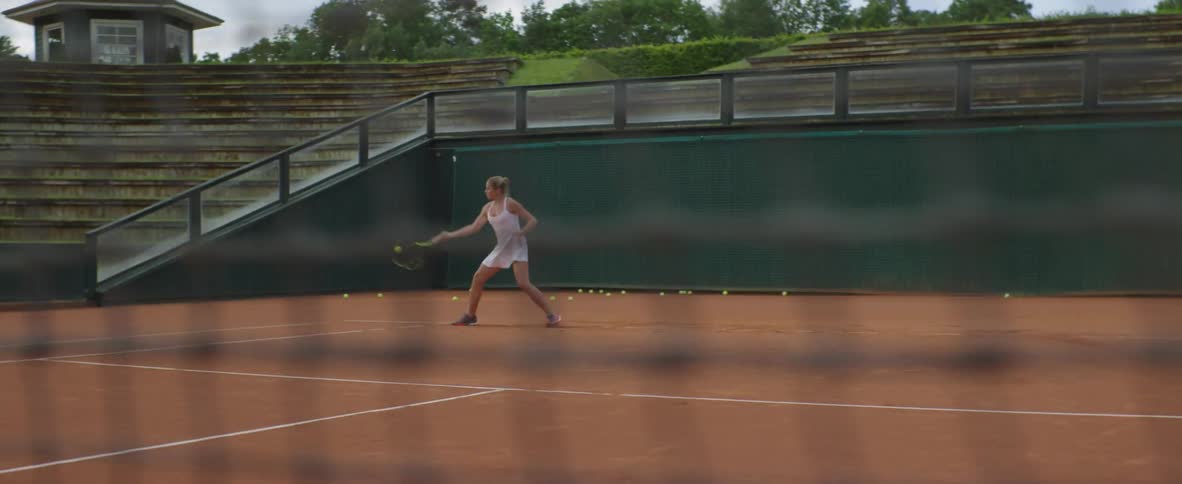 A tennis player runs back and forth across the court to volley tennis balls