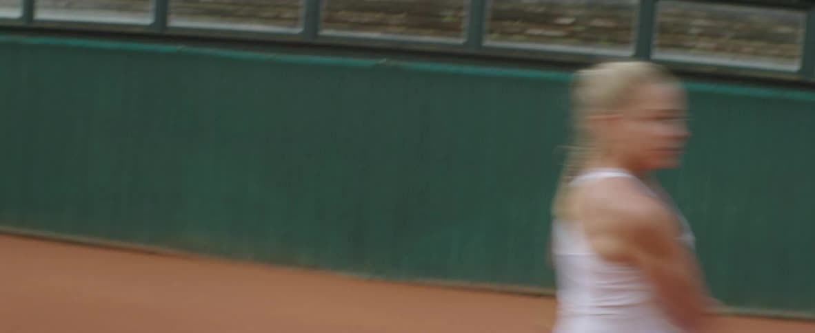 A tennis player volleys balls back and forth across the court