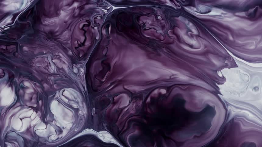 Purple paint expands over white paint to create swirl patterns