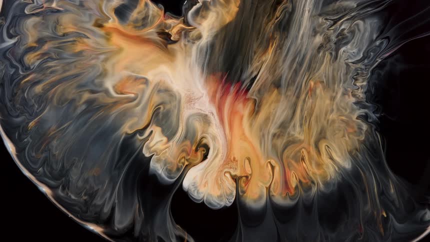 Blooming wave of orange and cream colored liquid ink expanding on a black background