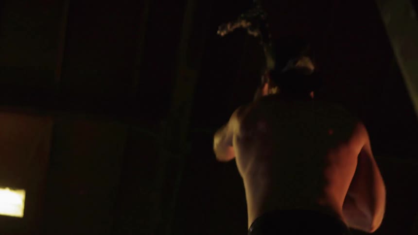 A man jumps and beings climbing a rope