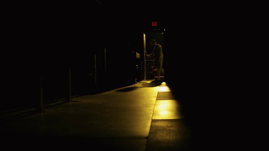 A man enters a dark room closing the door