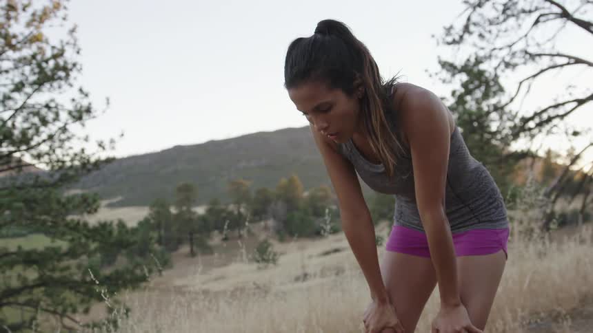 A woman runs downhill before stopping to rest