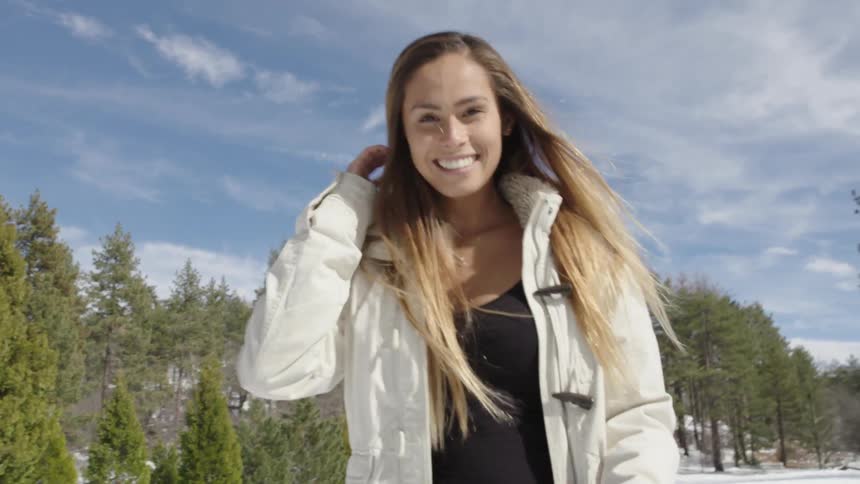 A woman smiling and prancing around in the snow
