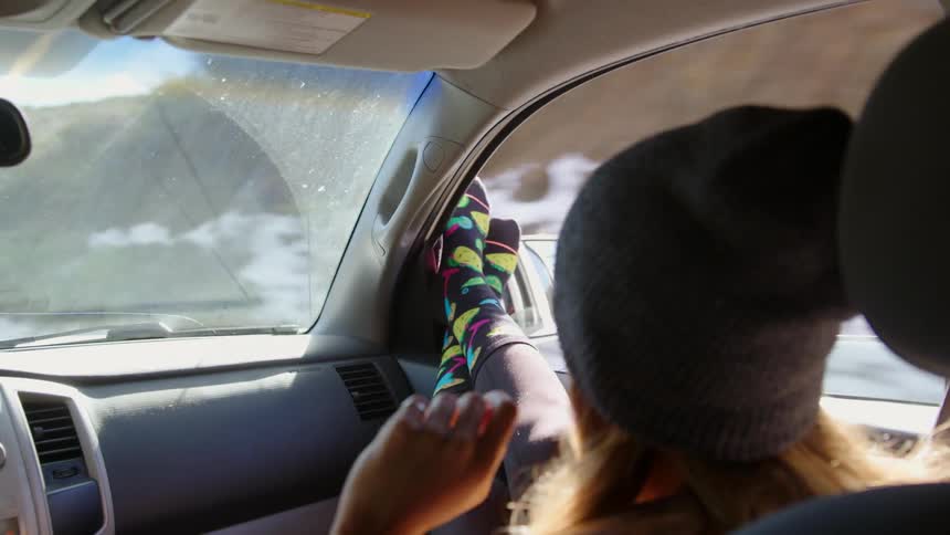 Woman riding in a car with her feet resting out of the window