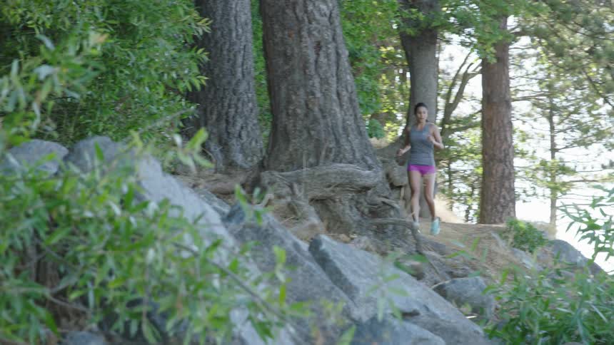 A woman jogs along a rocky trail in the woods