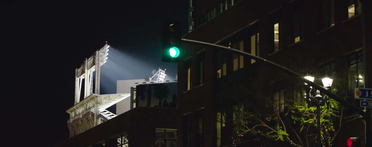 A traffic light changing as a bank of lights shines in the background