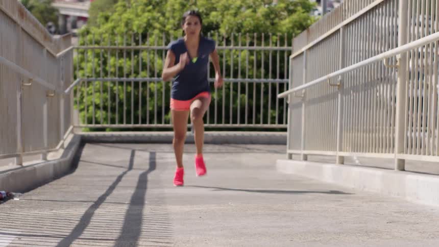 A woman runs up and around going over an overpass