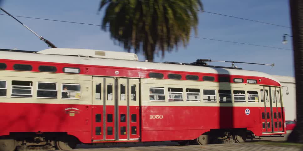 White red tram runs on rails along the streets of city and carries passengers