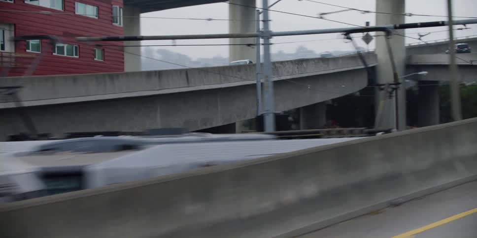 Cars travel on and off highway exit ramps near subway trolleys