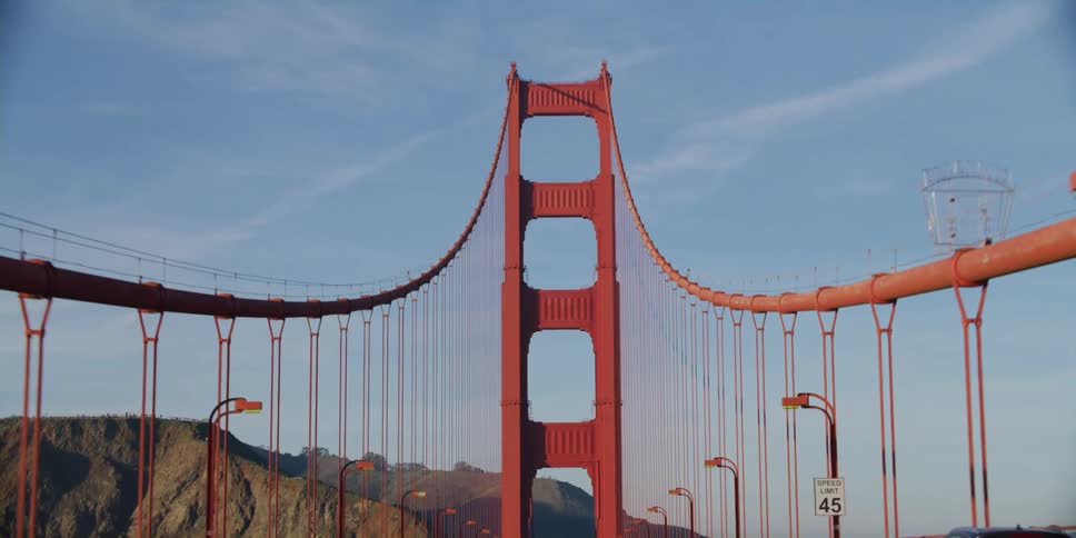 Cables and red tower of the golden gate bridge as traffic travels across