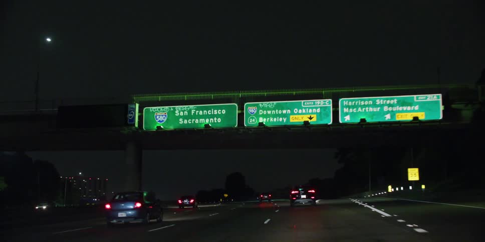 Vehicle drives on highway with overpass at night