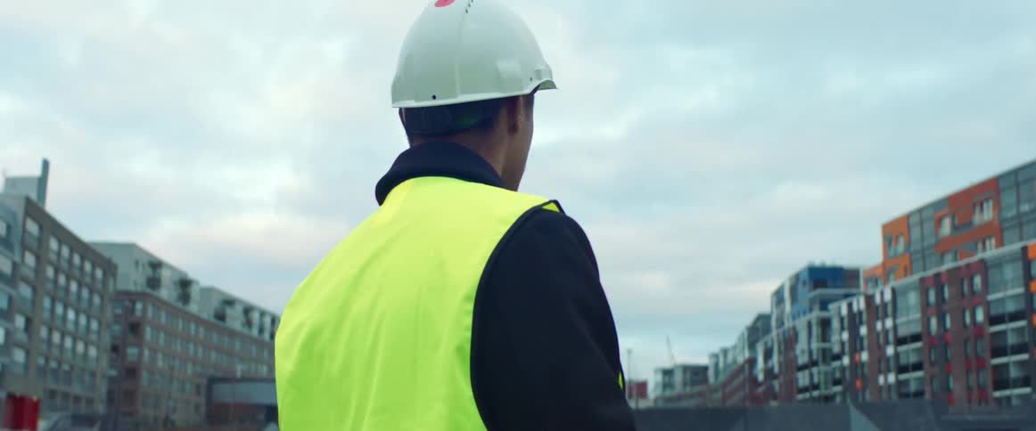 A construction worker stands outside the site of several high rises being built