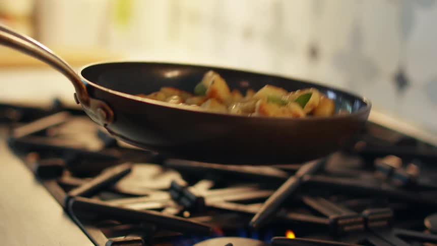 Shrimp tossed around while cooking on an iron pan over the kitchen range at home