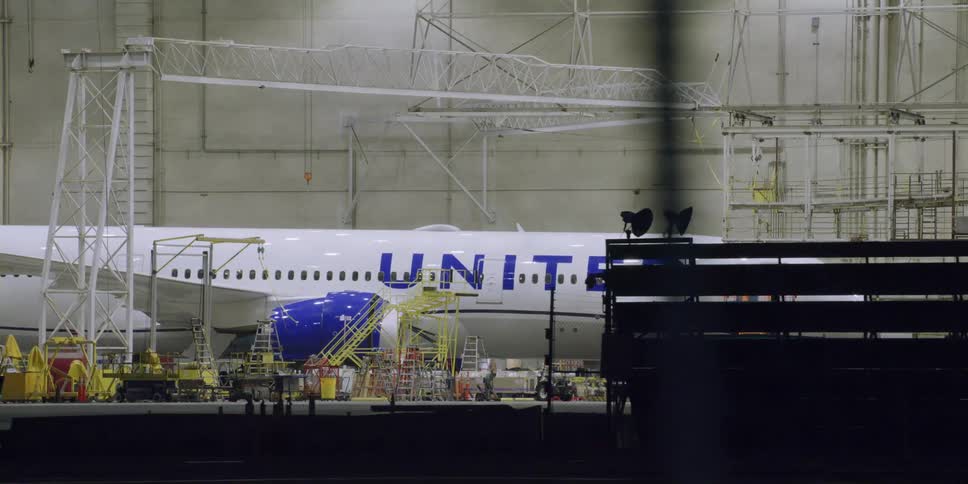 Commercial airplane parked inside a hangar on an airport at night