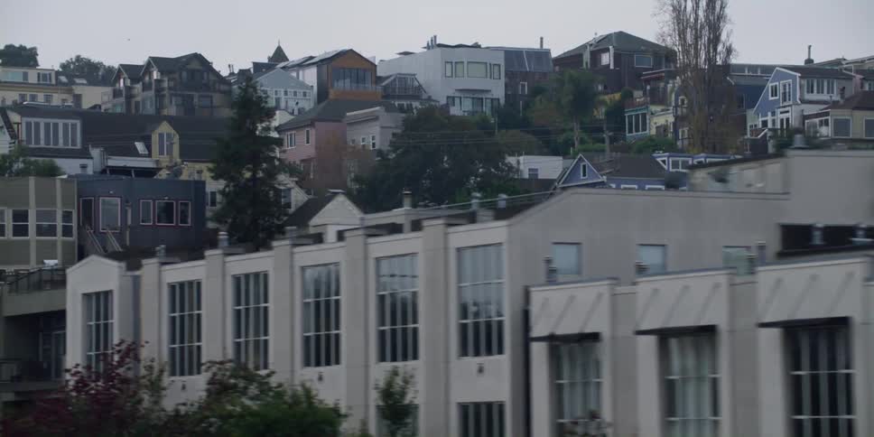 Apartment buildings and homes sit close together along a hill in the city