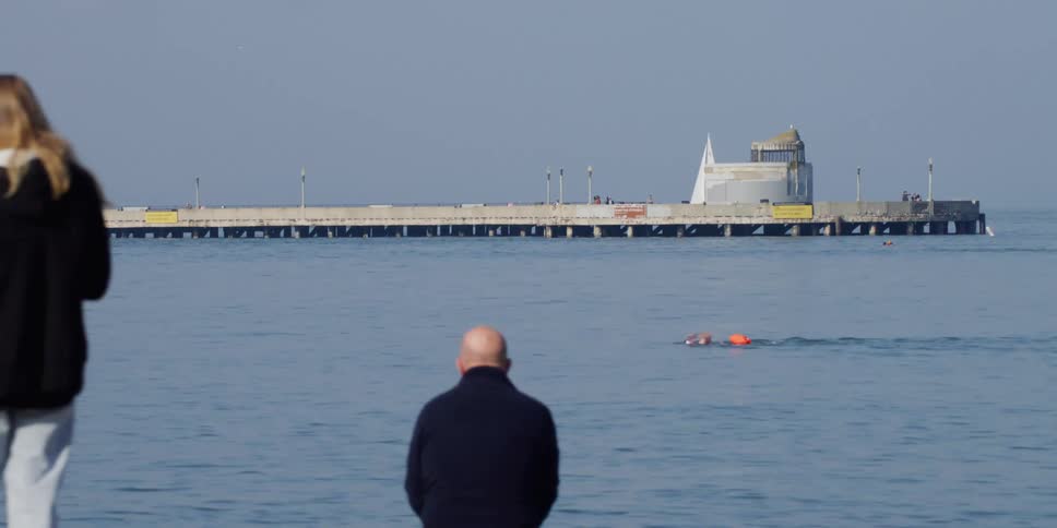 A person is swimming in the water by the port