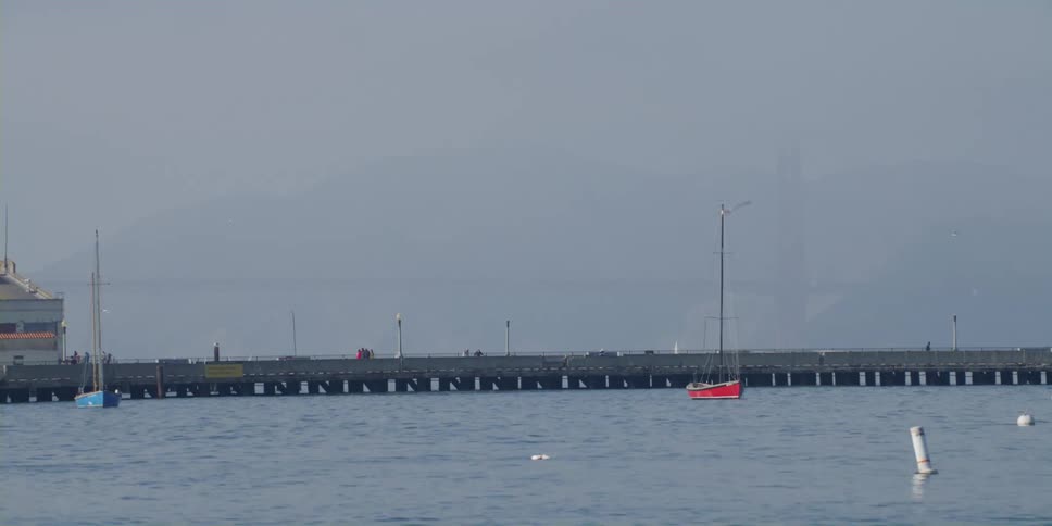 Red boat floating in the ocean close to a boardwalk at daytime