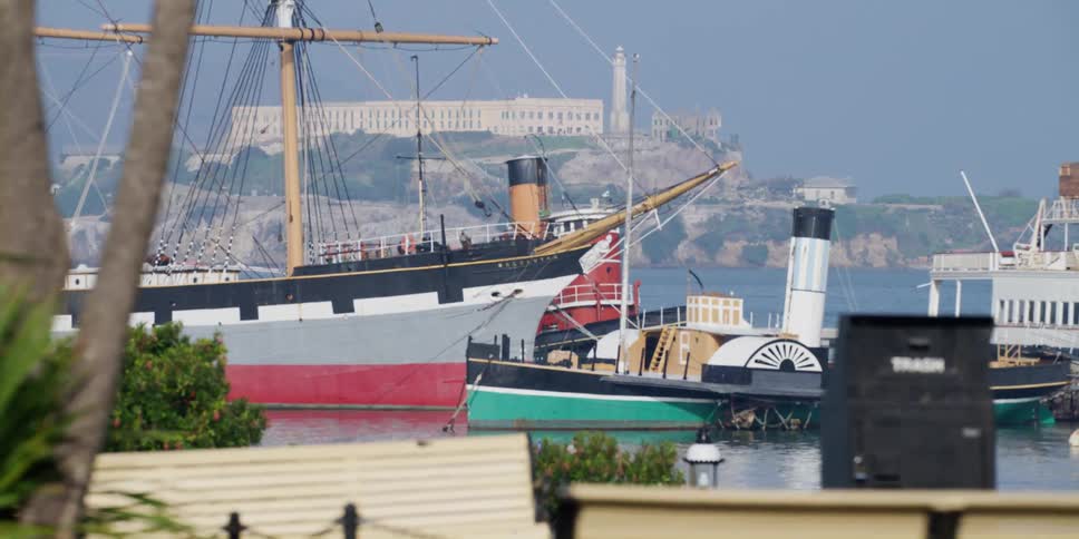 A woman runs along the coast and past a large ship docked in the ocean