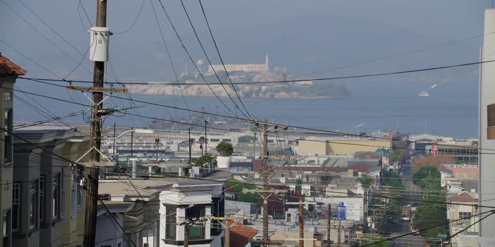 Apartment buildings and homes line the street of a coastal neighborhood on a hill