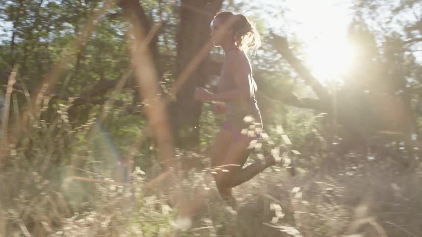 A female jogger runs through a wooded area