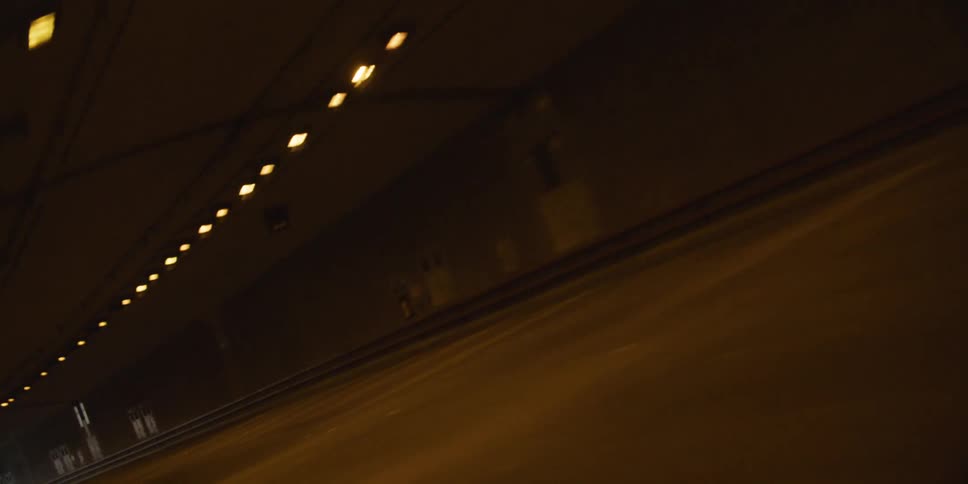 Twisting footage of vehicles driving inside a tunnel under yellow lights