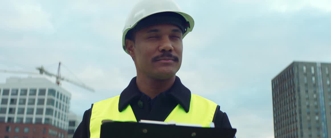 A construction worker is smiling outdoors during the daytime