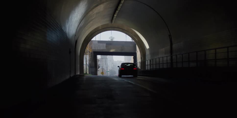 A car travels through a tunnel and under an overpass on a city highway