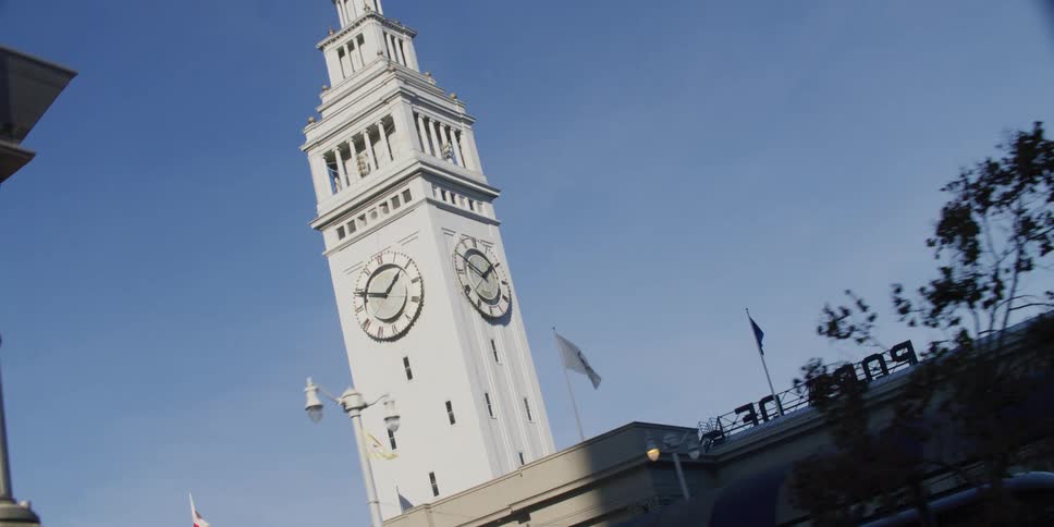 Flags wave in the breeze around the clock tower at the port of san francisco