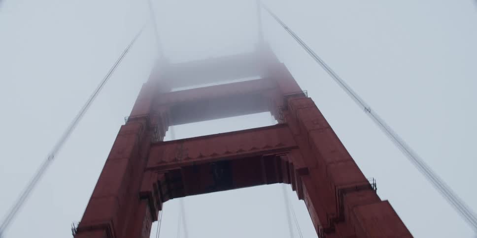 Traveling under the red tower of the golden gate bridge and looking up into the fog