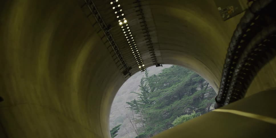 Twisting zooming footage of the exit of a tunnel going outdoors