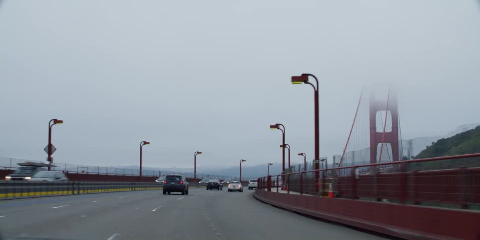 Vehicles commuting across the golden gate bridge on a foggy morning