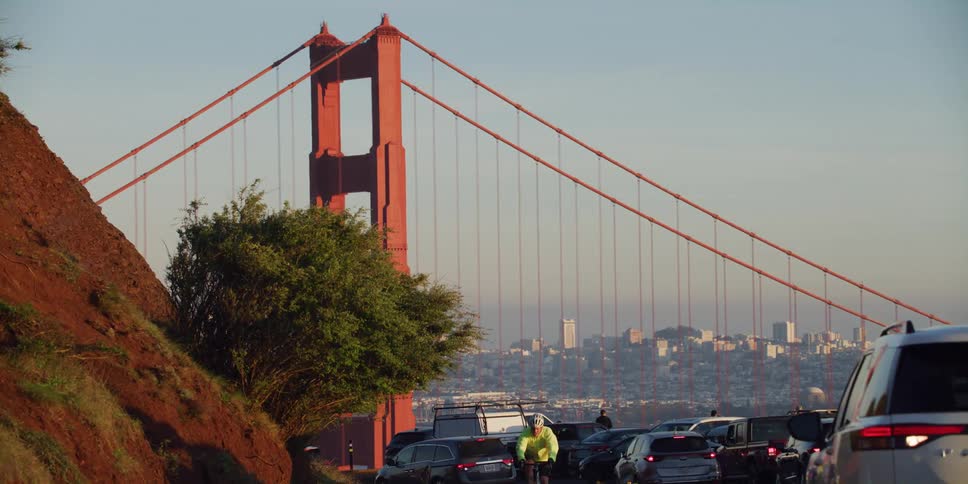 Cars are driving near a downtown bridge at dusk