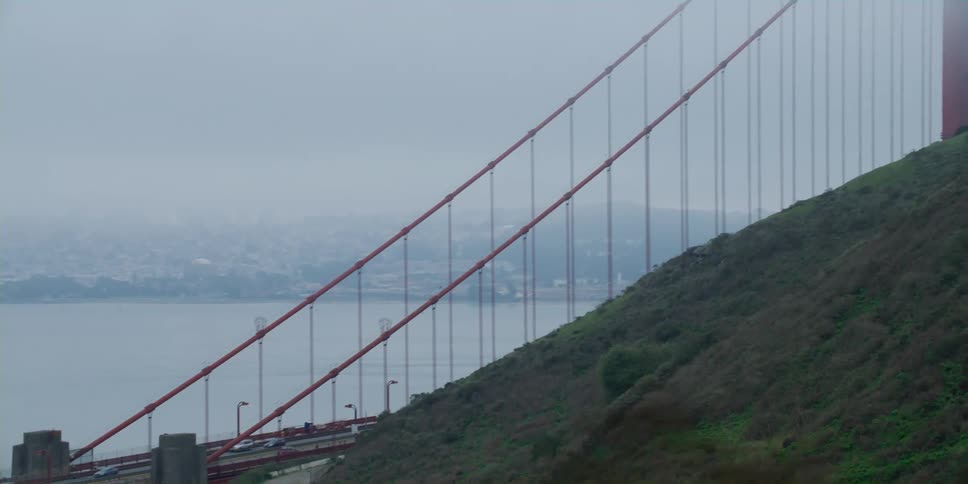 Vehicles drive down the golden gate bridge in heavy fog