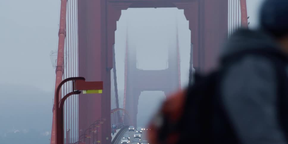 Vehicles cross the suspension bridge in fog