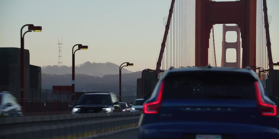 Cars travel across the golden gate bridge as tourists linger on the walkway