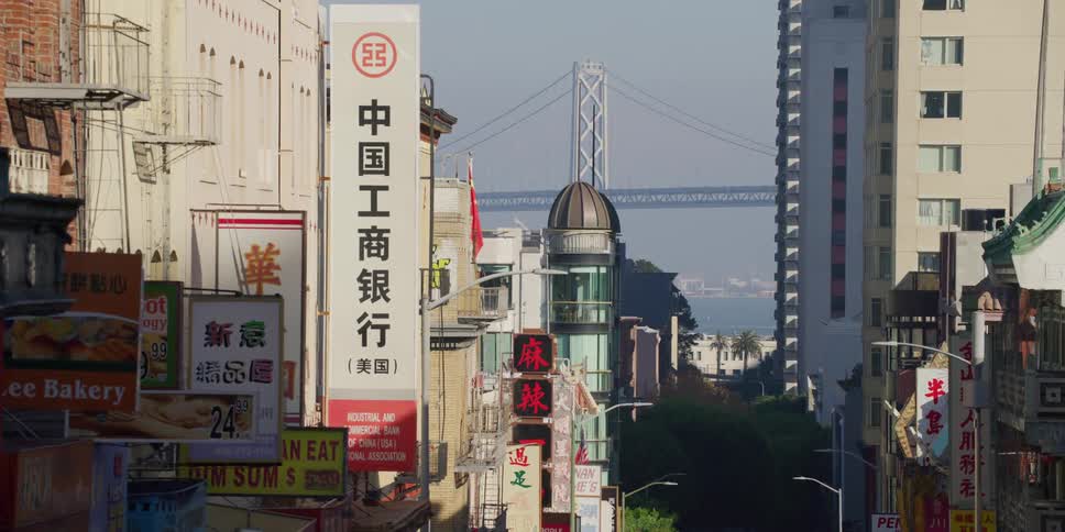 Businesses and apartment buildings line a city street on a hill