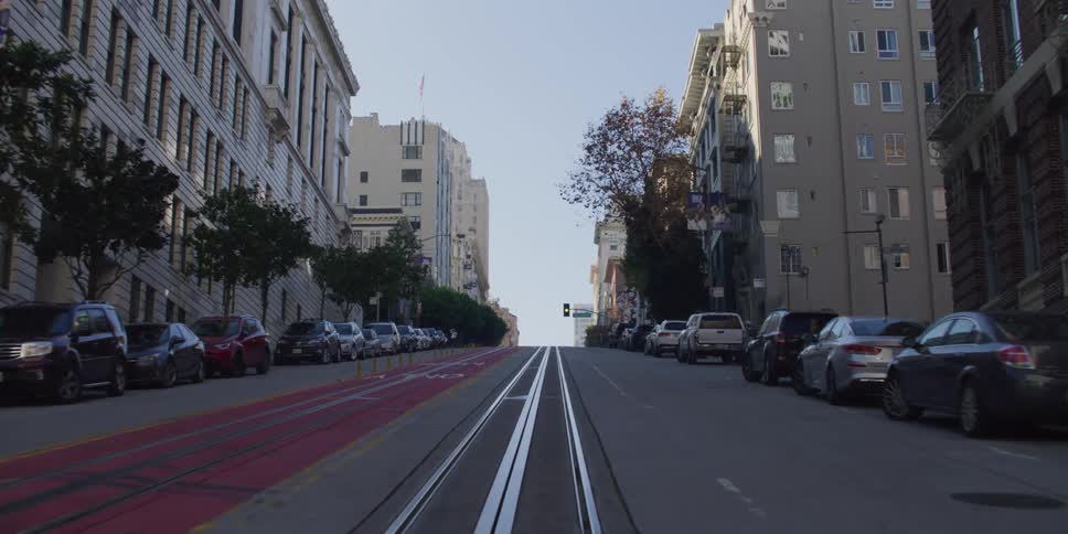 Parked cars line street leading between apartment buildings toward an intersection