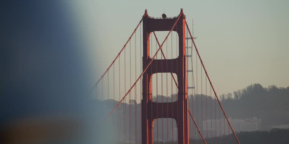 People and cars going past a suspension bridge