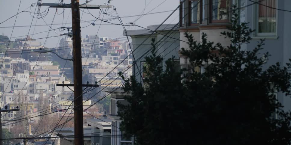 Hilly city streets with buildings poles and vehicles