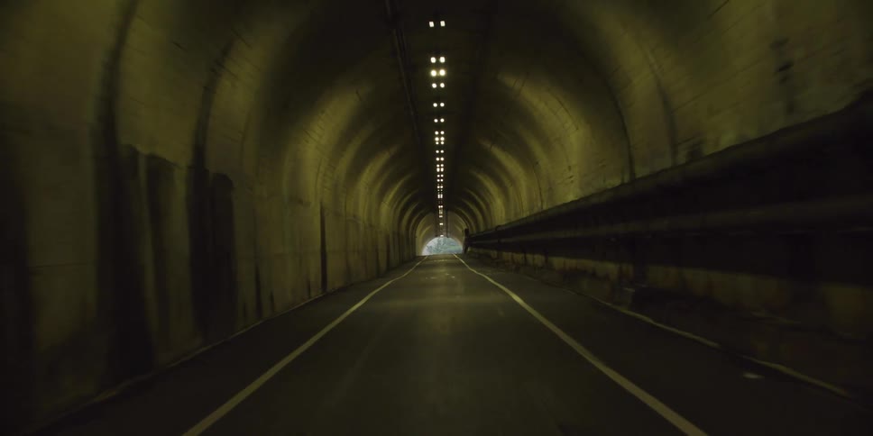 Driving through a narrow tunnel with lights above