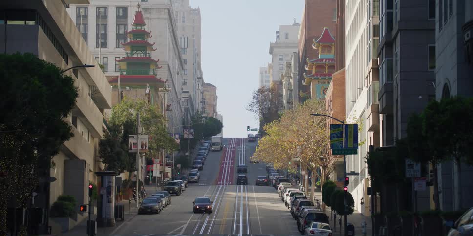 A trolley and personal vehicles drive through downtown