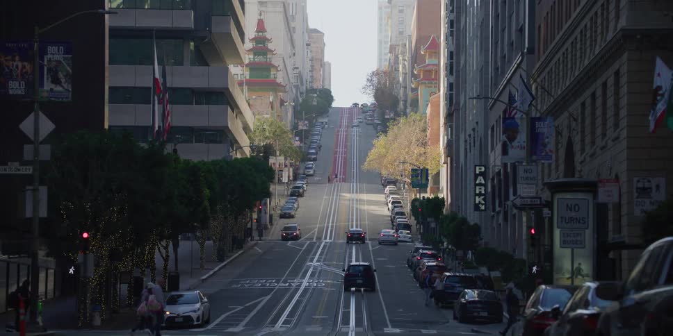 Busy steep street with cars and humans coming and going