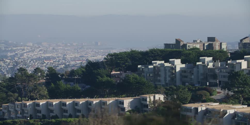 Fog covers city in the valley sitting in background of apartment topped hill