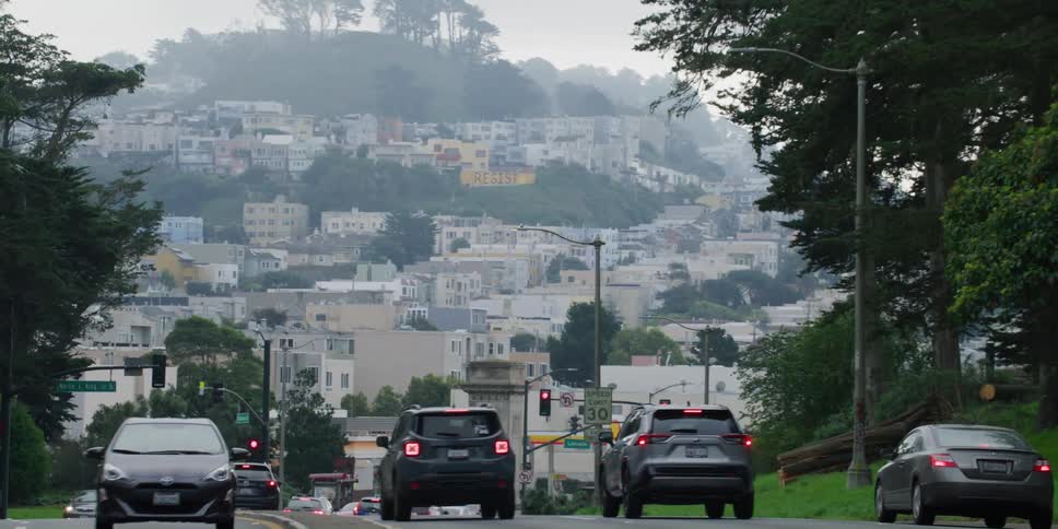 The vehicles are driving in traffic through town